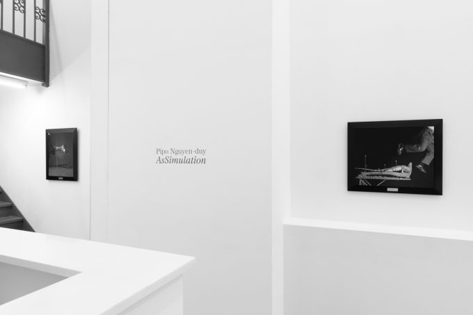 A photograph of black and white photographs in black frames hanging in a contemporary gallery setting.