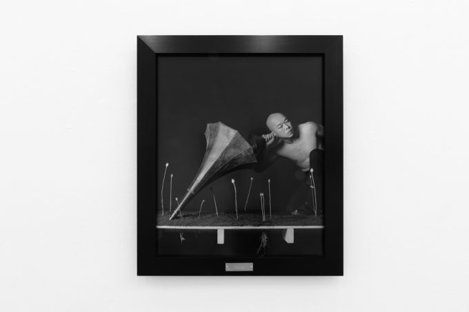 A photograph of black and white photographs in black frames hanging in a contemporary gallery setting.