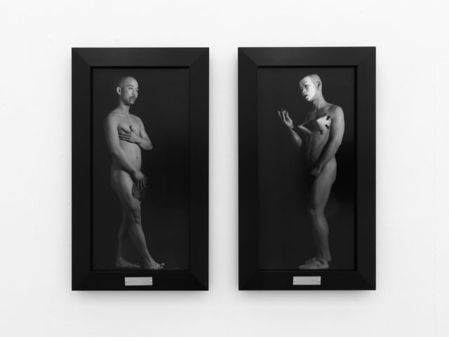 A photograph of black and white photographs in black frames hanging in a contemporary gallery setting.