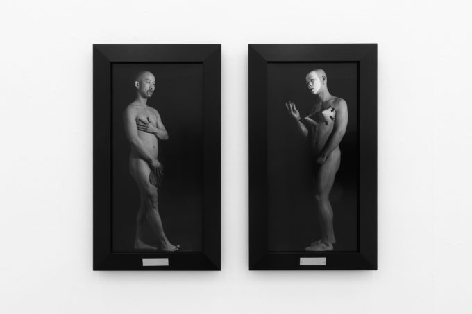 A photograph of black and white photographs in black frames hanging in a contemporary gallery setting.