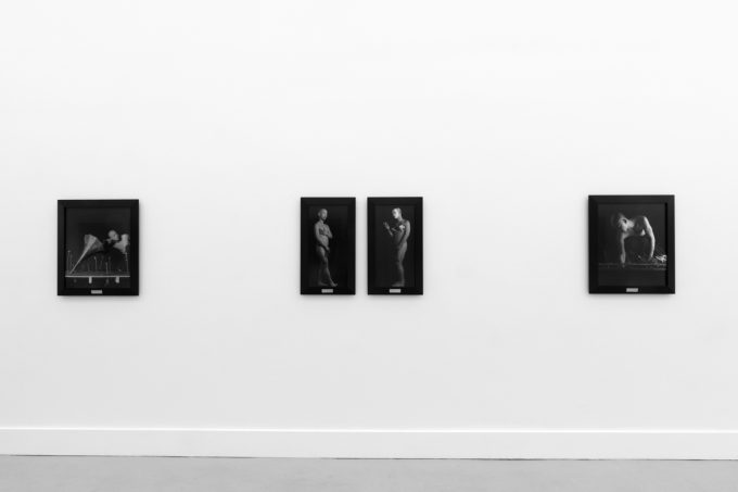 A photograph of black and white photographs in black frames hanging in a contemporary gallery setting.