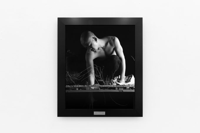 A photograph of black and white photographs in black frames hanging in a contemporary gallery setting.