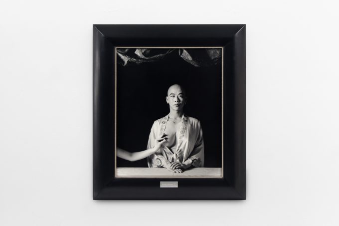 A photograph of black and white photographs in black frames hanging in a contemporary gallery setting.