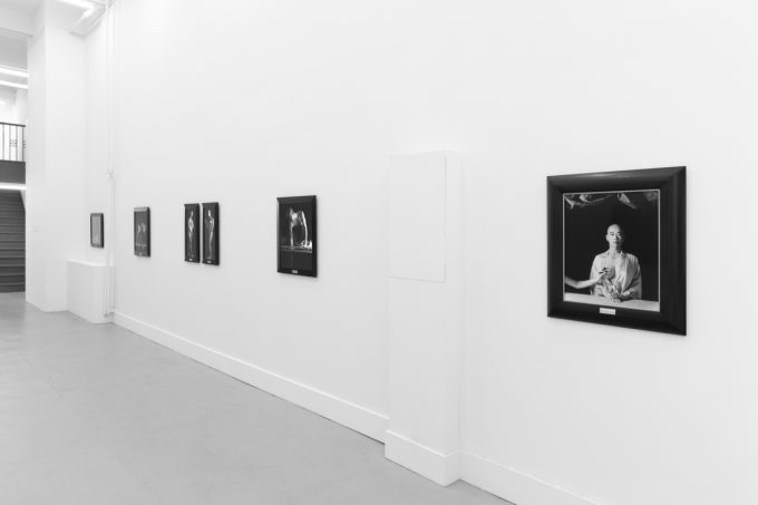 A photograph of black and white photographs in black frames hanging in a contemporary gallery setting.