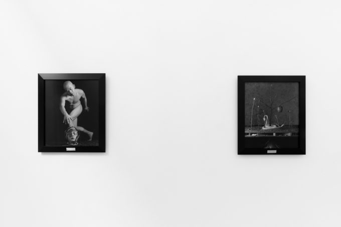 A photograph of black and white photographs in black frames hanging in a contemporary gallery setting.