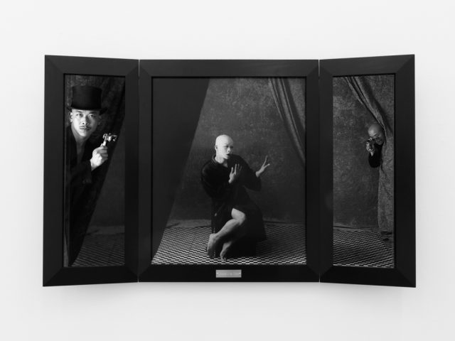 A photograph of black and white photographs in black frames hanging in a contemporary gallery setting.