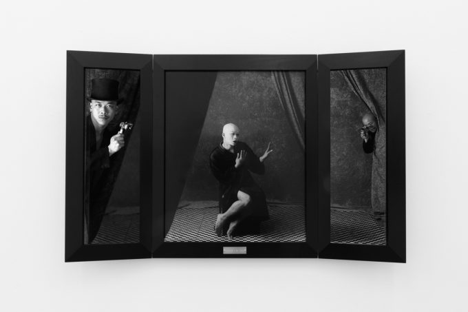 A photograph of black and white photographs in black frames hanging in a contemporary gallery setting.