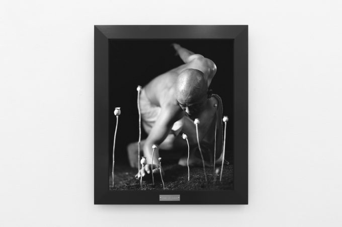 A photograph of black and white photographs in black frames hanging in a contemporary gallery setting.