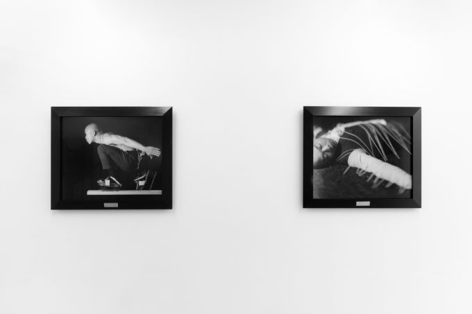 A photograph of black and white photographs in black frames hanging in a contemporary gallery setting.