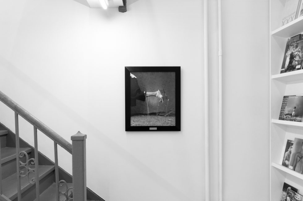 A photograph of black and white photographs in black frames hanging in a contemporary gallery setting.
