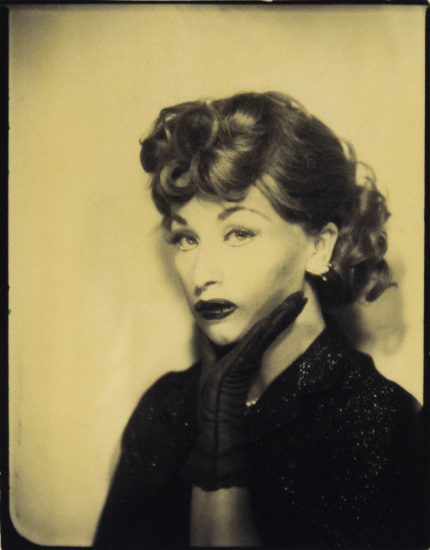 Cindy Sherman poses in sepia tones as Lucille Ball, with curled hair, dark makeup, and a gloved hand against her cheek.