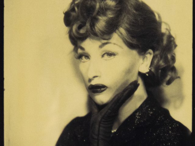 Cindy Sherman poses in sepia tones as Lucille Ball, with curled hair, dark makeup, and a gloved hand against her cheek.
