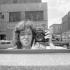 A black-and-white photo of a woman in a mirror on the street.