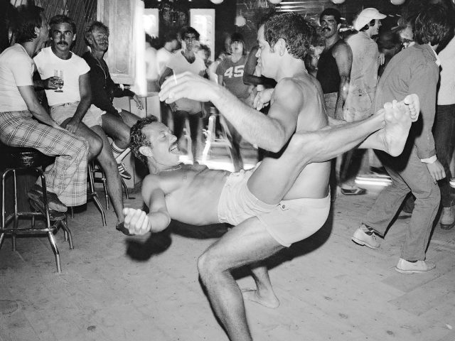 A black and white photograph of two men dancing in a club.