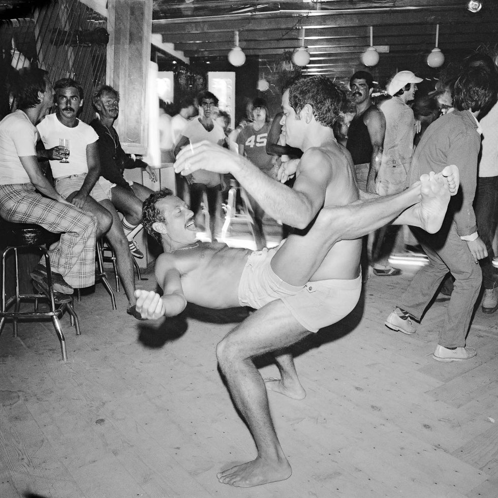 A black and white photograph of two men dancing in a club.