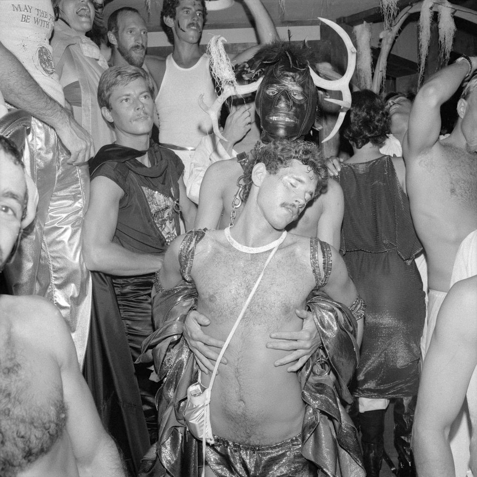 A black and white photograph of a man dancing on his own in the middle of a dance club.