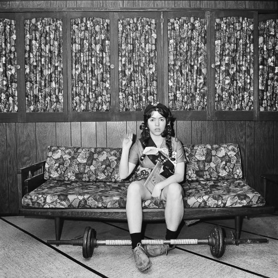 A black and white photograph of a girl sitting on a sofa doing the girl scout oath.