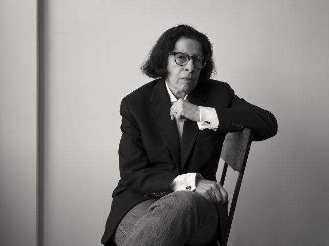 A black and white photograph of a skeptical looking person sitting in a chair.