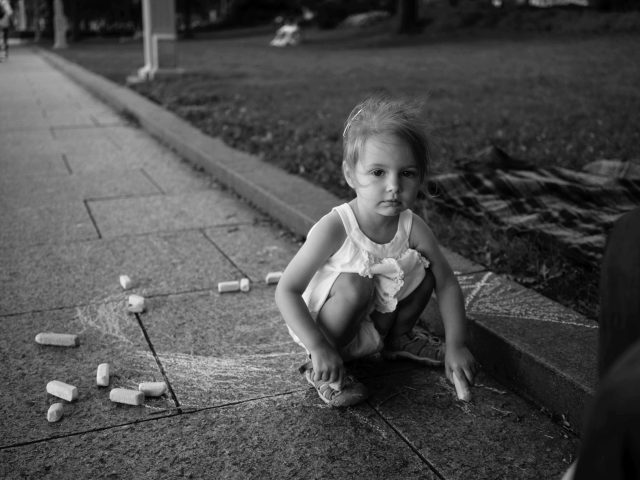 A black and white image of a girl playing with challk.