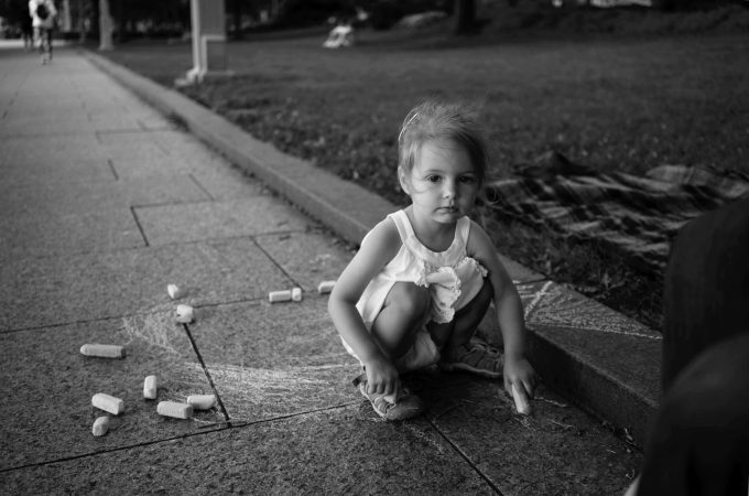 A black and white image of a girl playing with challk.