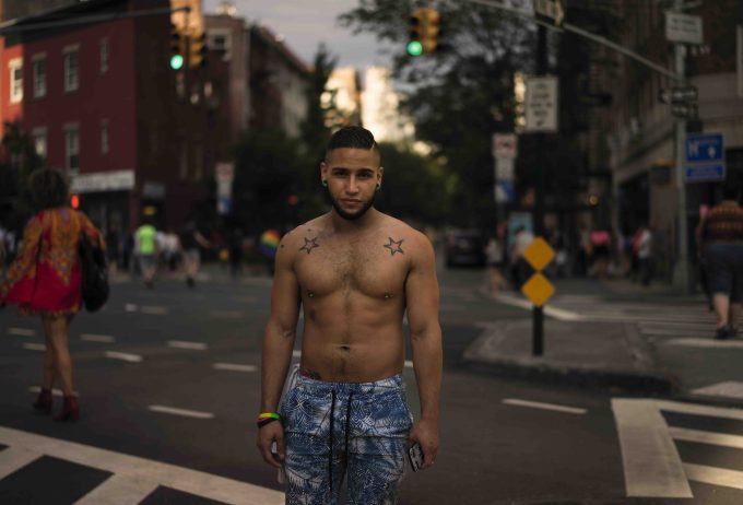 A handsome young man stands in a New York City street with star tattoos on his skin.
