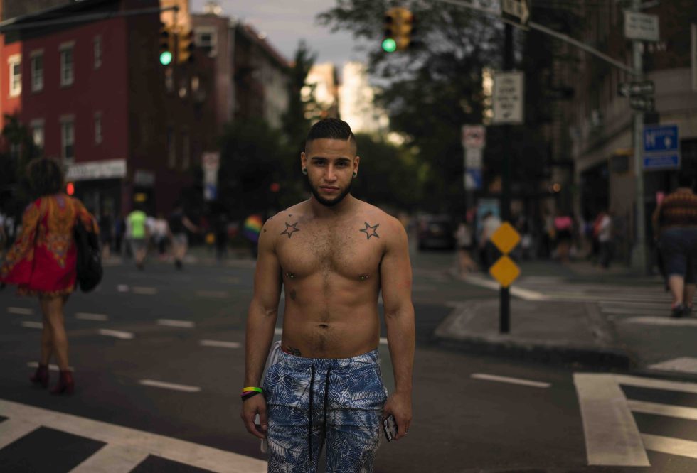 A handsome young man stands in a New York City street with star tattoos on his skin.