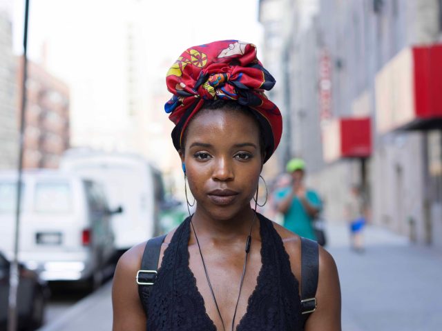 A photograph of a young woman on the street staring at the camera.