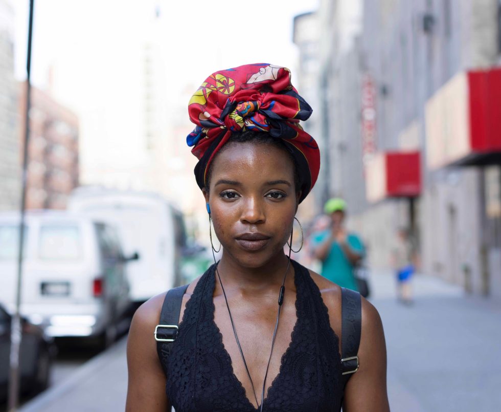 A photograph of a young woman on the street staring at the camera.