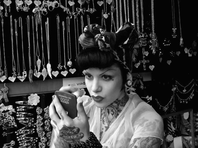 A black and white photograph of a person touching up their makeup.