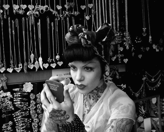 A black and white photograph of a person touching up their makeup.