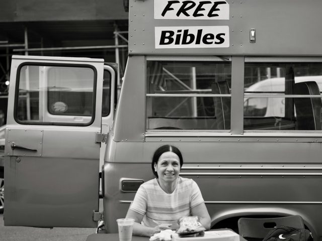 A black and white photograph of a woman handing out free bibles.