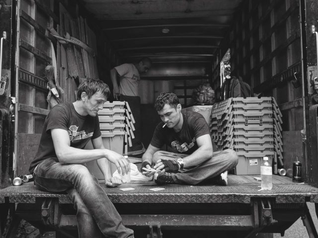 A black and white photograph of movers playing cards in the back of a truck.