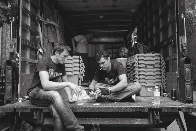 A black and white photograph of movers playing cards in the back of a truck.