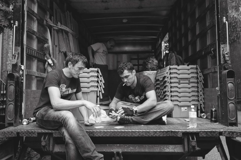 A black and white photograph of movers playing cards in the back of a truck.