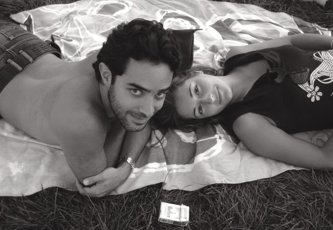 A black and white photograph of two young lovers in the grass.