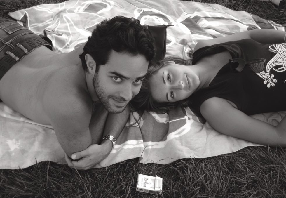 A black and white photograph of two young lovers in the grass.