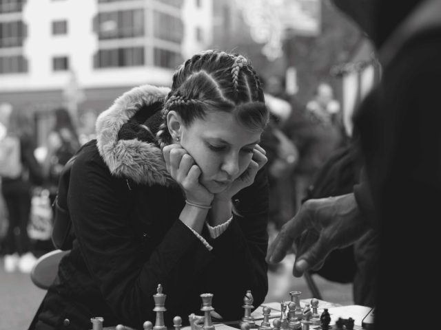A black and white photograph of a young woman playing chess.