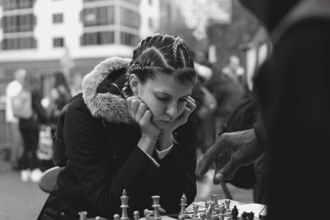A black and white photograph of a young woman playing chess.