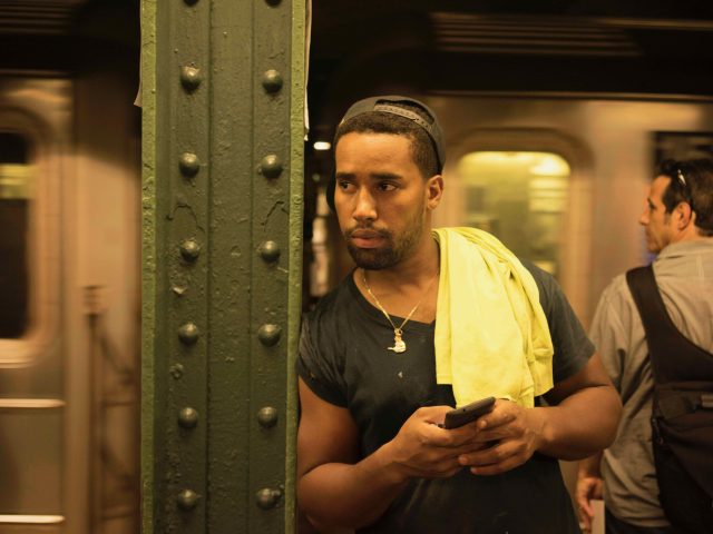 A color photograph of a construction worker waiting for the subway.