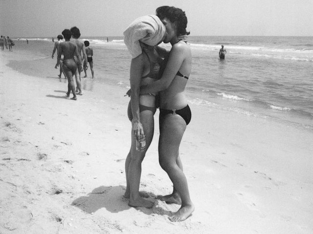 black and white photograph of two women kissing on a beach.