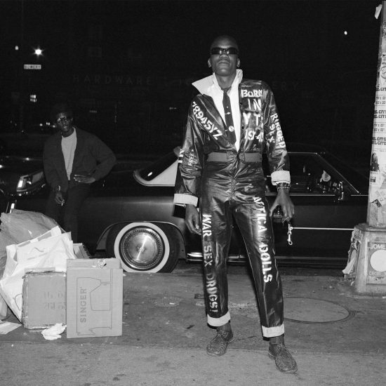 A black and white portrait of a man in a jumpsuit with text in white paint on it.