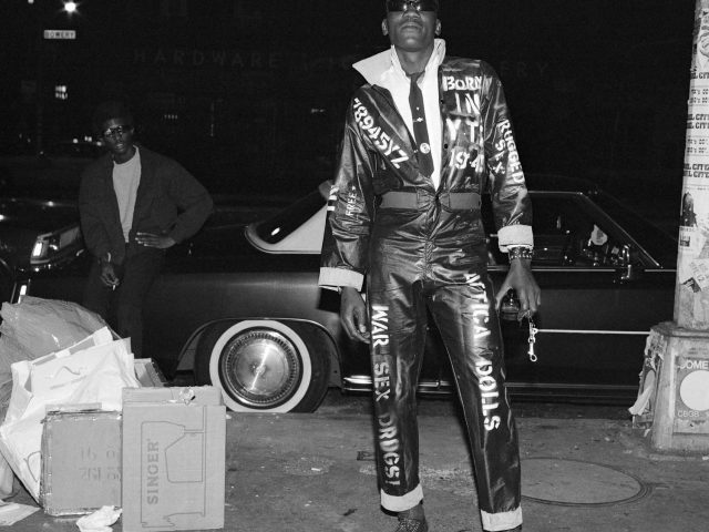 A black and white portrait of a man in a jumpsuit with text in white paint on it.