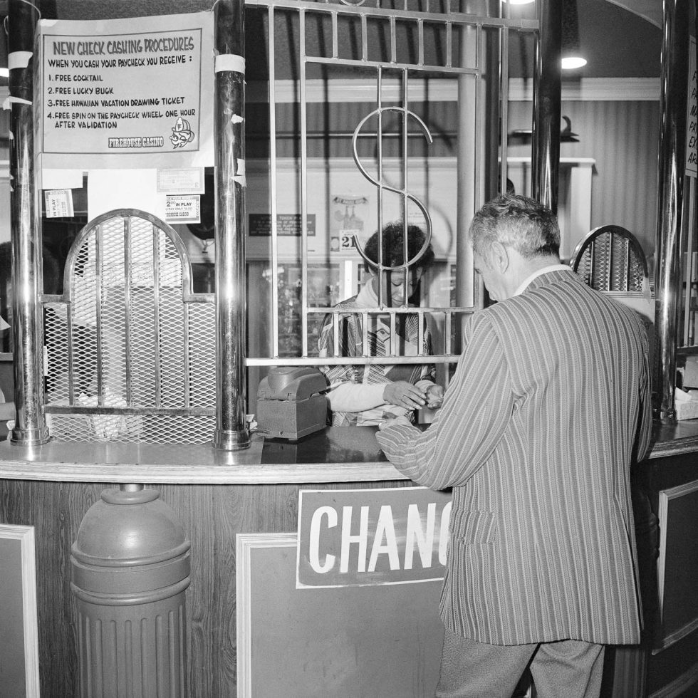 A black and white photograph of a man cashing a check.