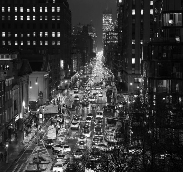 A black and white photograph of a traffic jam on a busy city street at night.