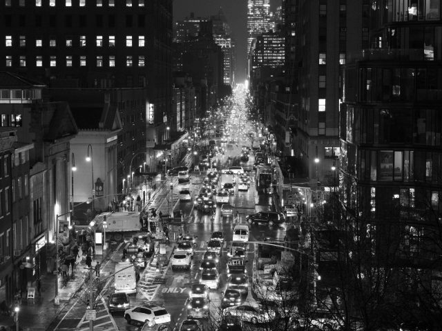 A black and white photograph of a traffic jam on a busy city street at night.