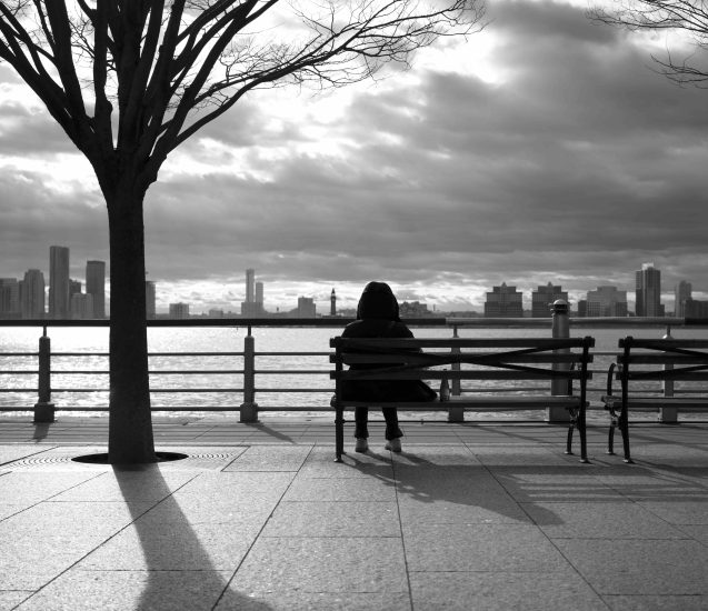 A black and white photograph of a person sitting in front of the Hudson River.