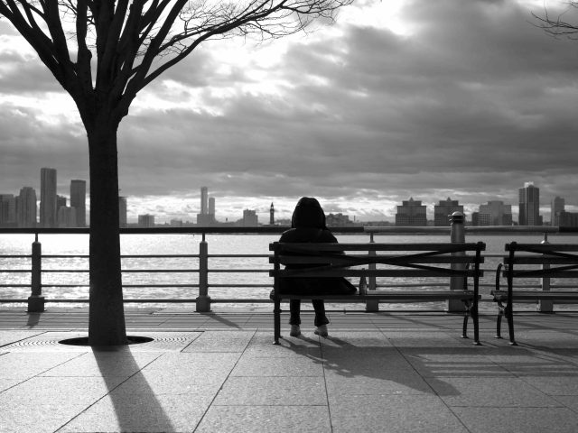 A black and white photograph of a person sitting in front of the Hudson River.