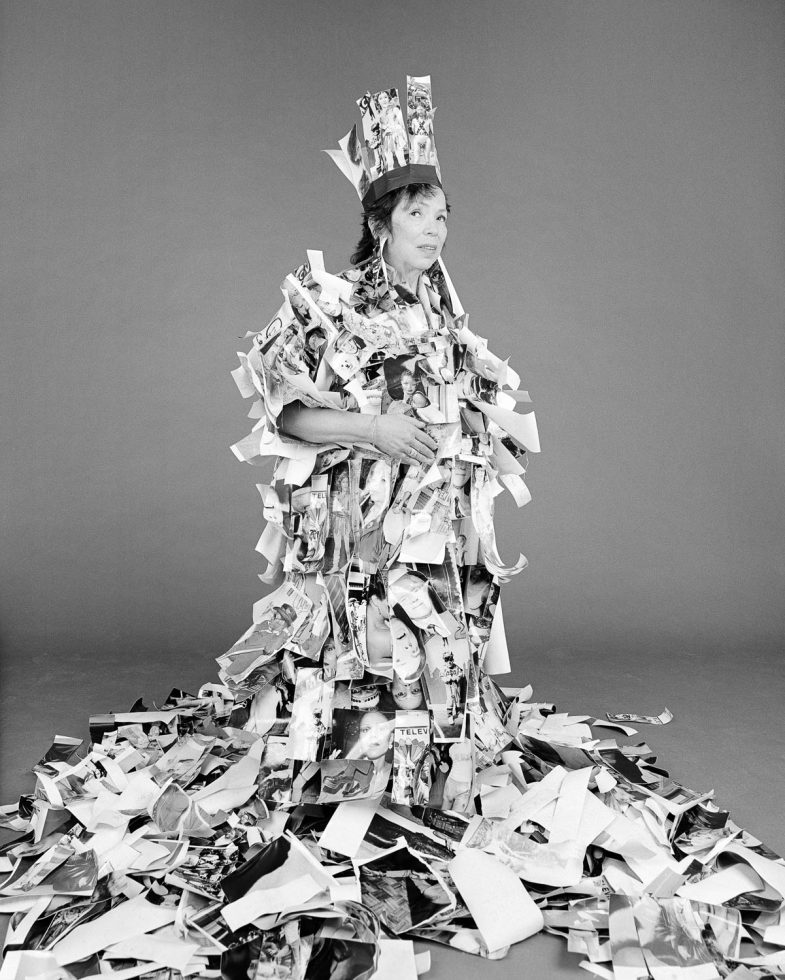A black and white photograph of a woman covered in small black and white photographic prints.