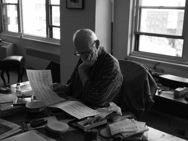 An old man sitting at a desk studying classical music.