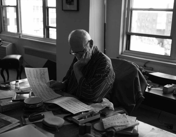 An old man sitting at a desk studying classical music.